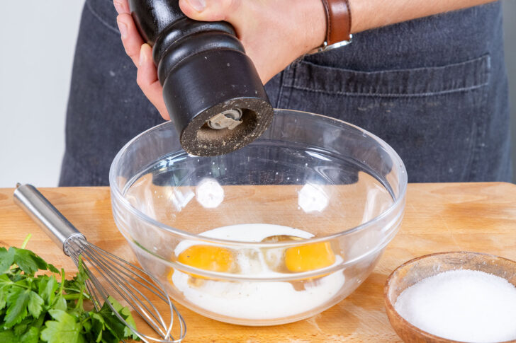 Eier und Milch in einer Schüssel verrühren und mit Salz, Pfeffer und Muskatnuss würzen