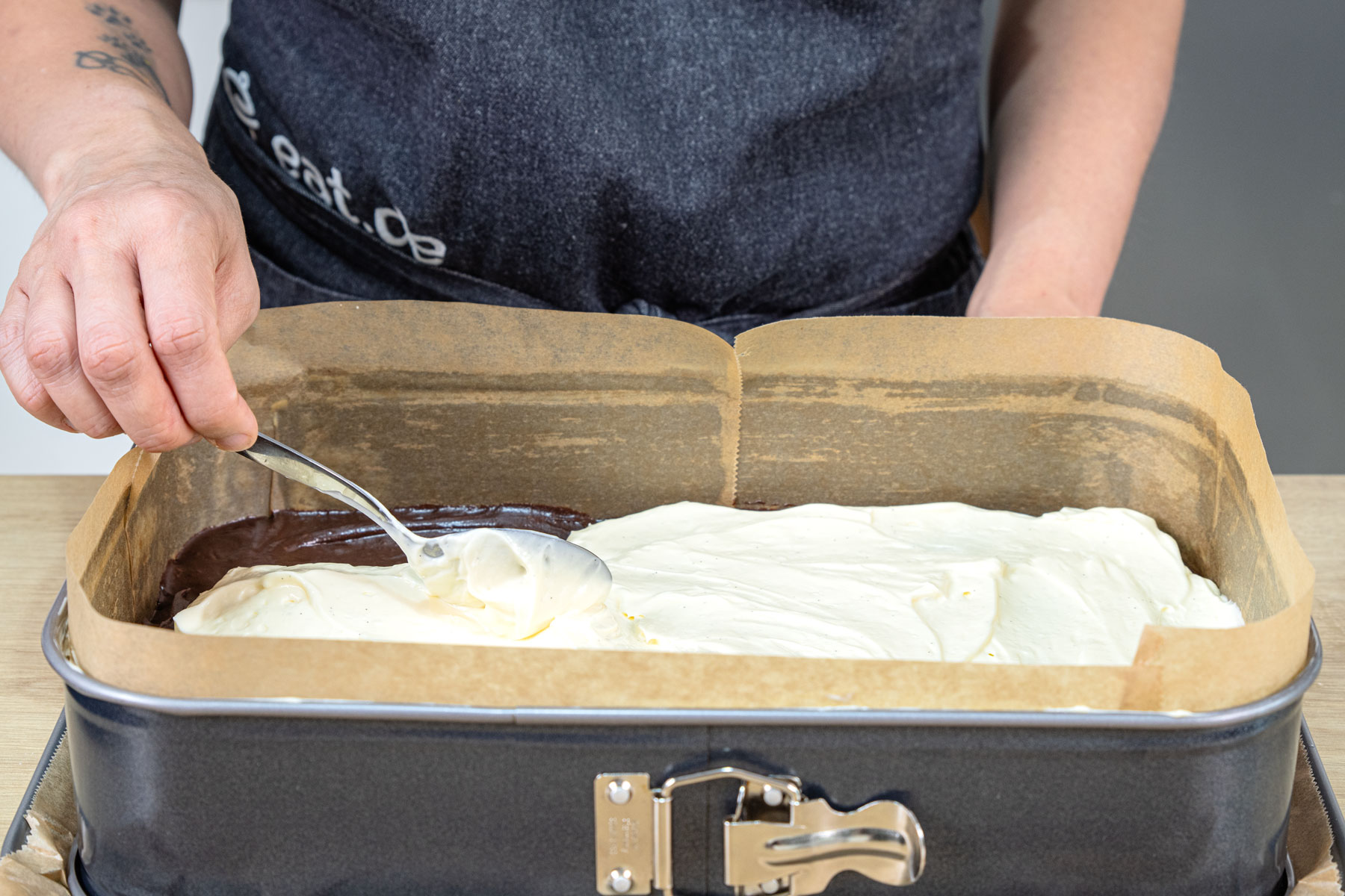 Cheesecake-Masse vorsichtig auf Brownie-Teig verteilen