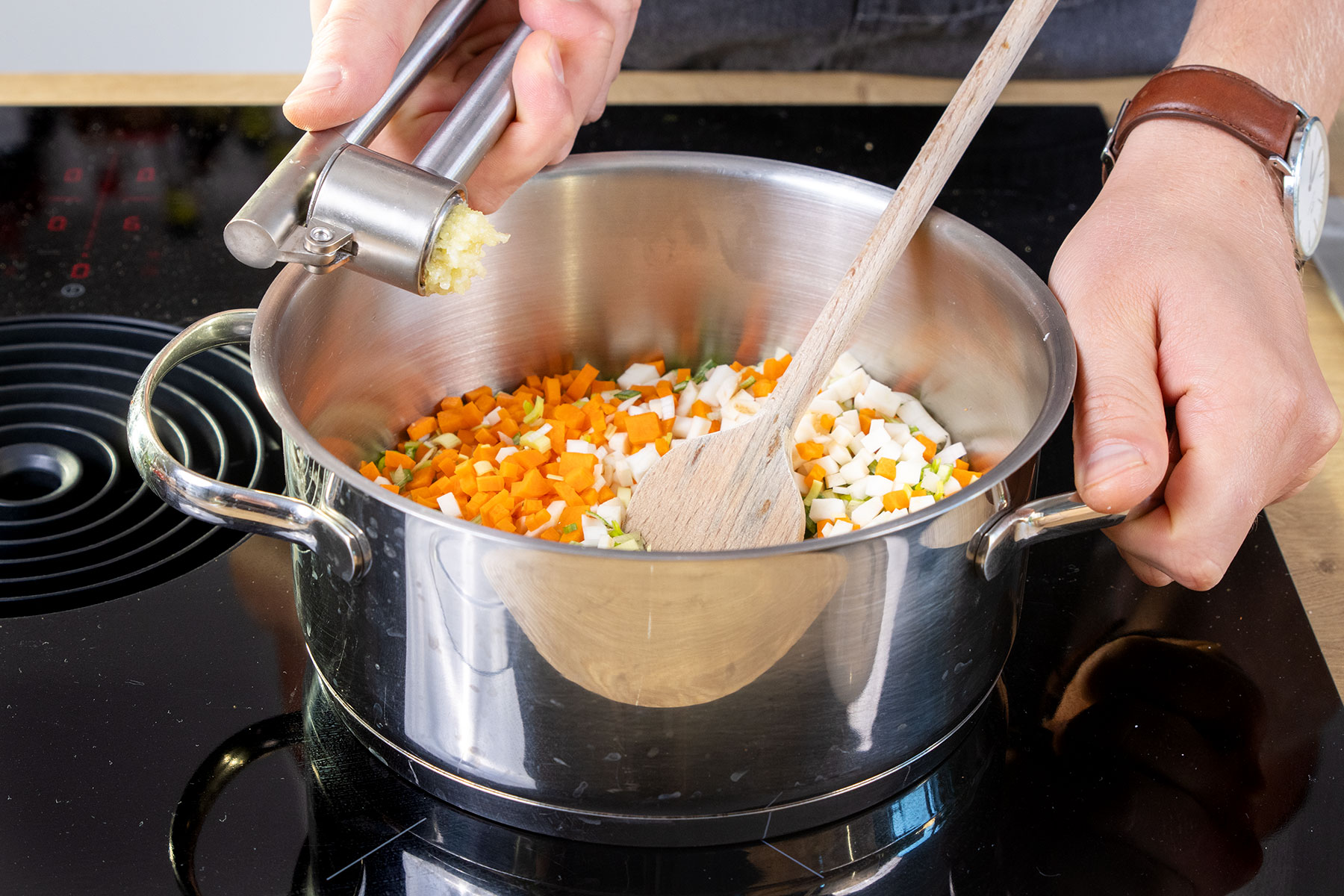 Knoblauch zu den Gemüsewürfeln pressen