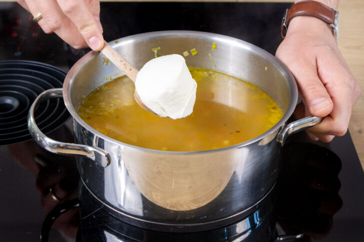 Crème fraîche zur Grünkernsuppe geben