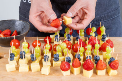 Käse, Obst und Tomaten auf die Spieße aufspießen