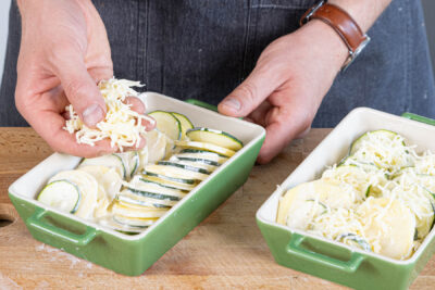 Kartoffel-Zucchini-Gratin mit Käse bestreuen und im Backofen gratinieren