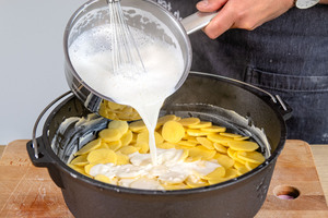 Sahnesoße über Kartoffeln geben