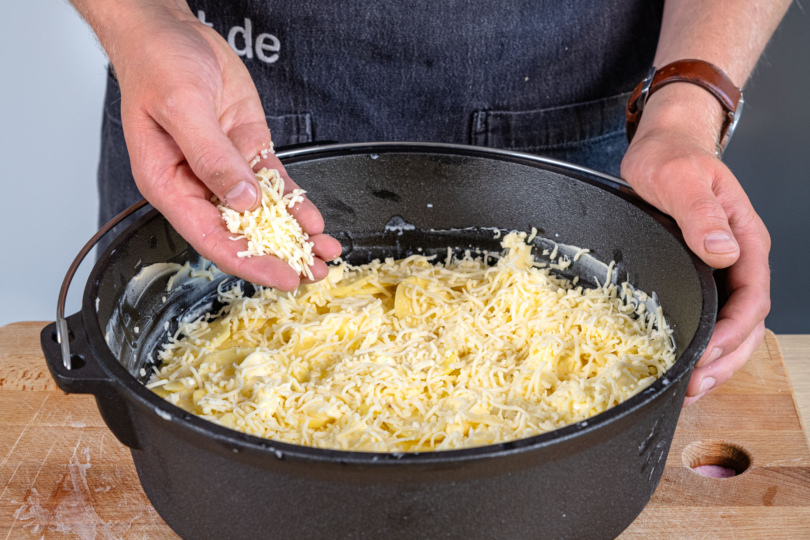 Kartoffelgratin aus dem Dutch Oven mit Käse bestreuen