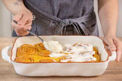 Kürbis-Zimtschnecken mit Frosting bedecken