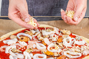 Meeresfrüchte-Pizza mit Käse belegen