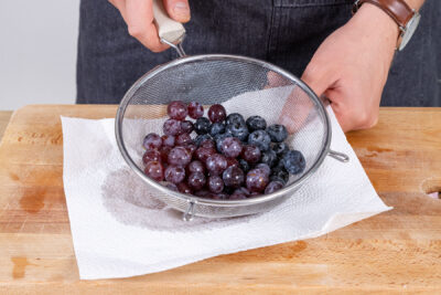 Blaubeeren und Weintrauben abtropfen