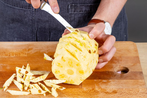 Augen der Schale aus der Ananas schneiden