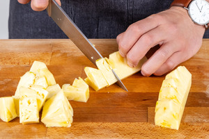 Ananas für die Obstspieße in Stücke schneiden