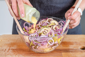 Dressing über Schweizer Wurstsalat geben