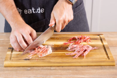 Salami und Schinken in feine Streifen schneiden.