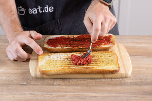 Das Tomatenmark auf dem Ciabatta verstreichen.