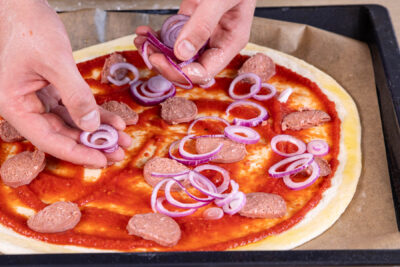 Zwiebeln & Sucuk auf Pizza verteilen