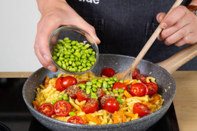 Tomaten und Edamame mit in die Pfanne geben.