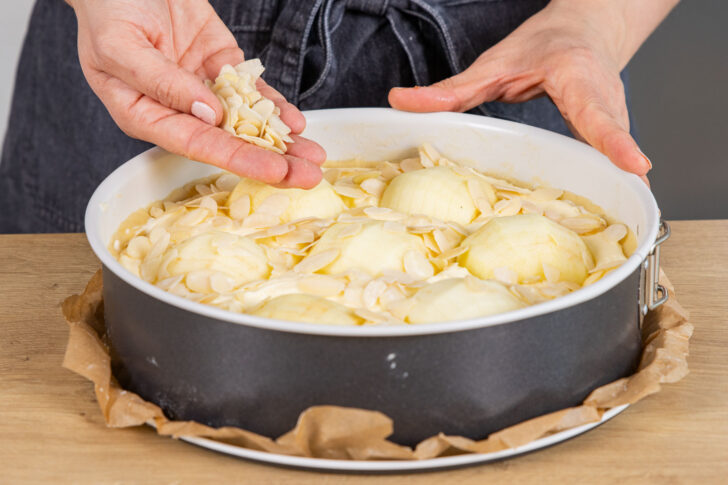 Äpfel und Mandeln auf Kuchen geben