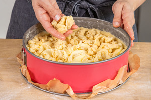 Streusel über Apfelkuchen geben