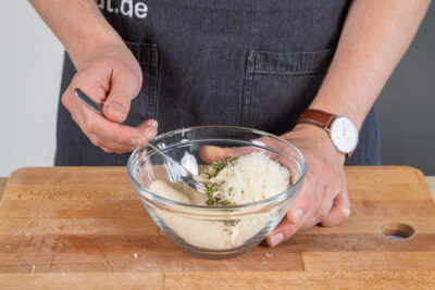 Kräuter mit Käse und Paniermehl mischen