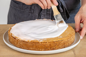 Gedeckten Apfelkuchen mit Zuckerguss bestreichen