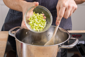 Sellerie in den Topf zur Zwiebel und zum Knoblauch geben