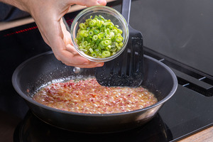 Frühlingszwiebel in die Pfanne geben