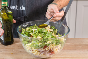 Öl zum italienischen Nudelsalat mit Rucola geben