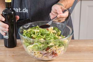 Balsamico zum italienischen Nudelsalat mit Rucola geben