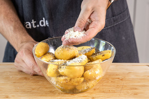 Parmesan über Kartoffeln verstreuen