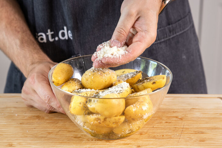 Parmesan über Kartoffeln verstreuen