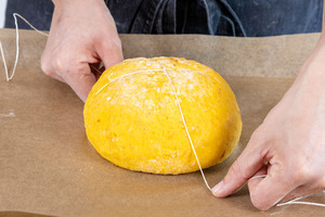 Schnur kreuzförmig um das Kürbisbrot wickeln