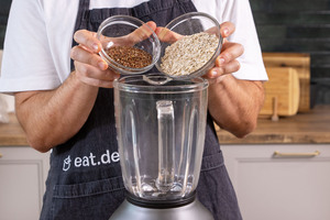 Haferflocken und Leinsamen in den Mixer geben