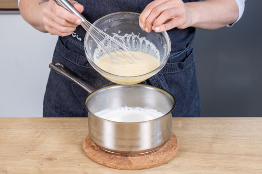 angerührtes Puddingpulver zur aufgekochten Milch geben