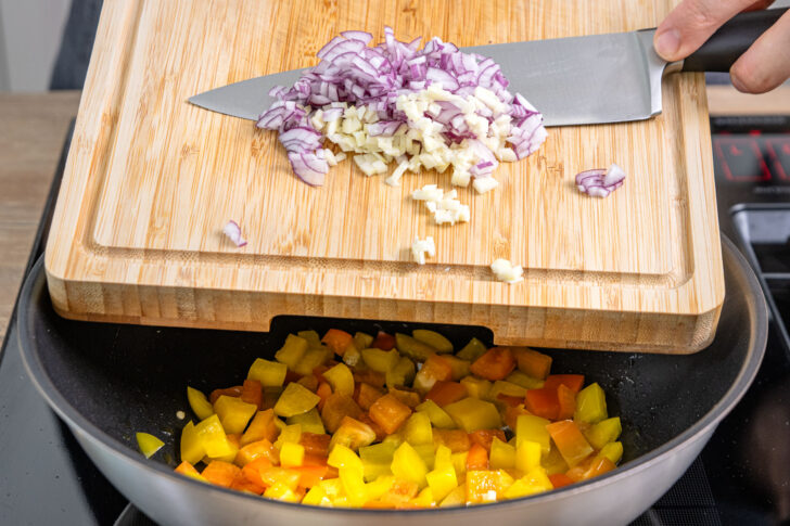 Zwiebel und Knoblauch in die Pfanne geben