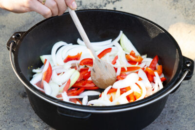 Zwiebeln, Knoblauch und Paprika im Dutch Oven anbraten.