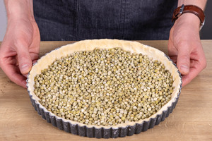 Backerbsen auf Quiche-Boden verteilen