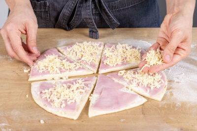 Teig mit Schinken und Käse belegen