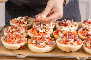 Pizzabrötchen mit Käse bestreuen