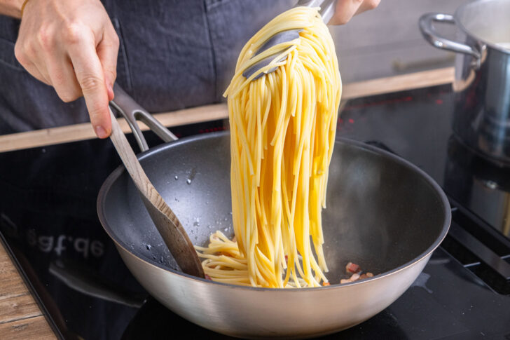 Spaghetti in die Pfanne geben