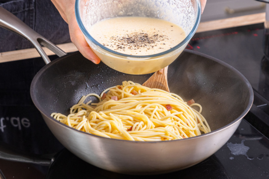 Carbonara-Soße zu den Spaghetti geben
