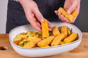 Fischstäbchen auf Gemüse verteilen