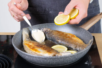 Butter und Zitronenscheiben in die Pfanne geben.