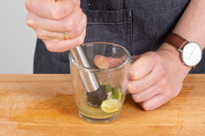 Limettenstücken mit Saft und Rohrzucker zerstoßen