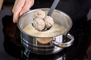 Königsberger Klopse nach Omas Rezept in die Sauce geben