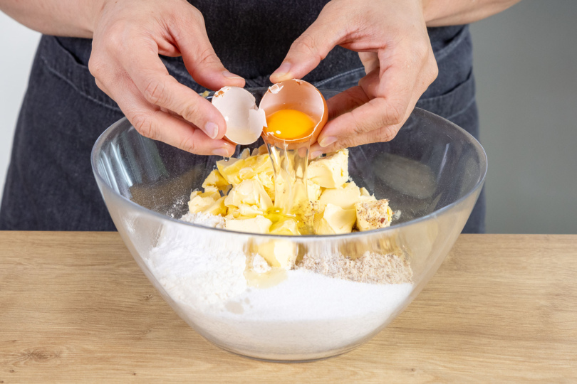 Ei zum Mehl, Margarine und den gemahlenen Nüssen geben