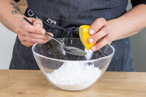 Zitronensaft zum Puderzucker geben