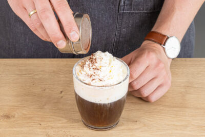 Pharisäer Kaffee mit Sahne und Kakaopulver garnieren