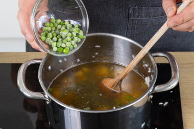 Erbsen und Gemüsebrühe mit in den Topg geben und kochen