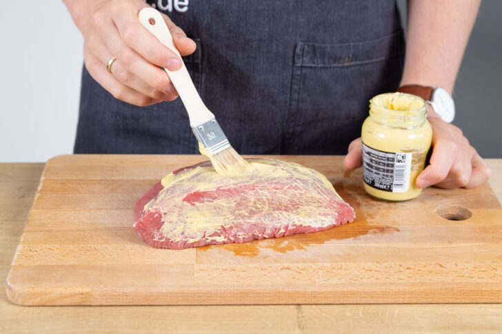 Den Braten mit Senf einstreichen.