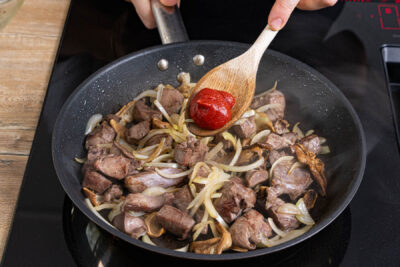 Tomatenmark und Mehl zum Ragout geben