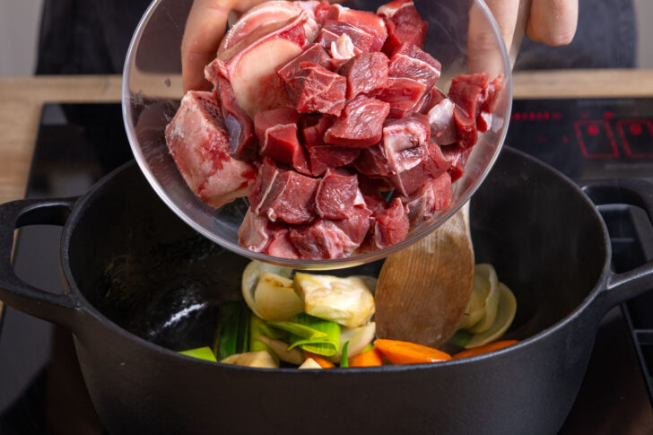 Suppenfleisch und Knochen in Bräter geben