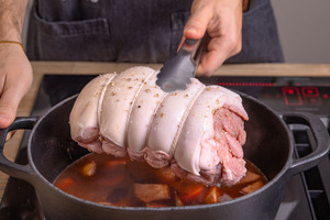 Spanferkelrollbraten in den Bräter geben